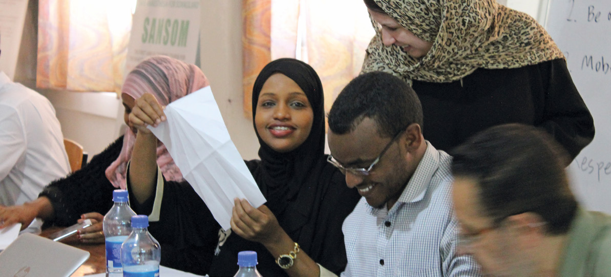 Participants at a faculty-development workshop discussing a paper-folding exercise.